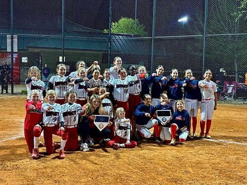 Youth softball team posing with awards at night