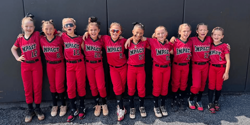 Girls' softball team in red uniforms smiling.
