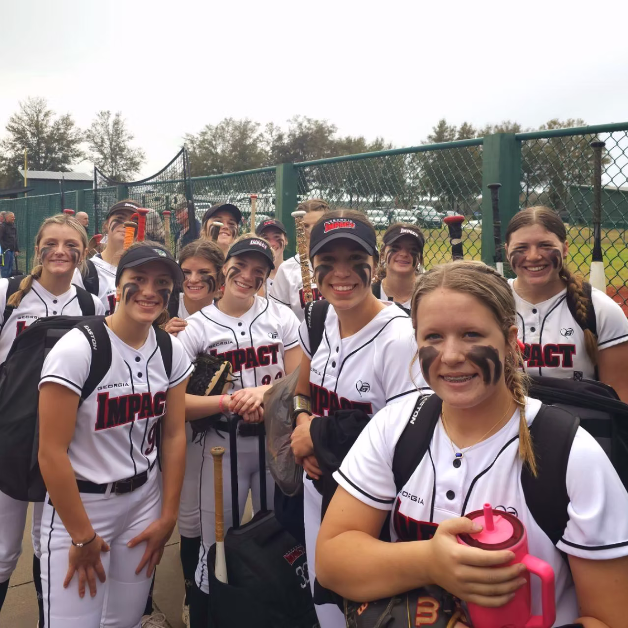 Softball team smiling and posing together outdoors.