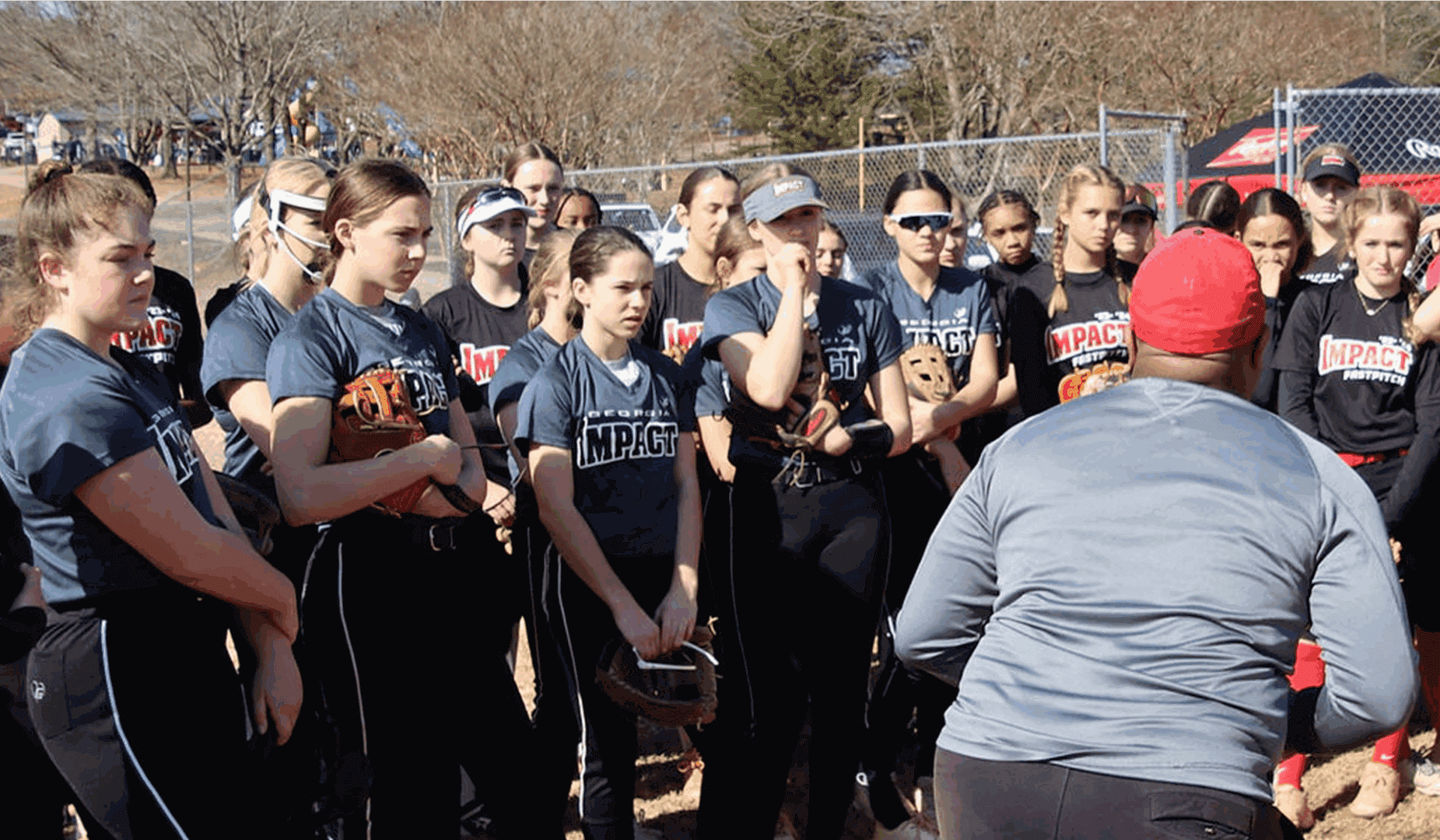 Softball team listens to coach on field.
