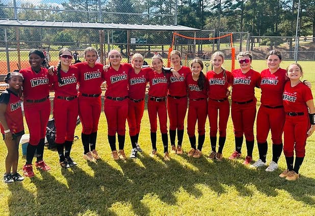 Softball team posing in red uniforms outdoors.