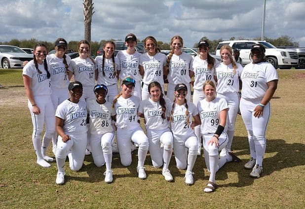 Softball team posing in white uniforms outdoors.