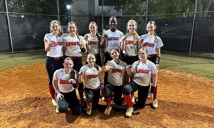 Softball team posing on field at night.