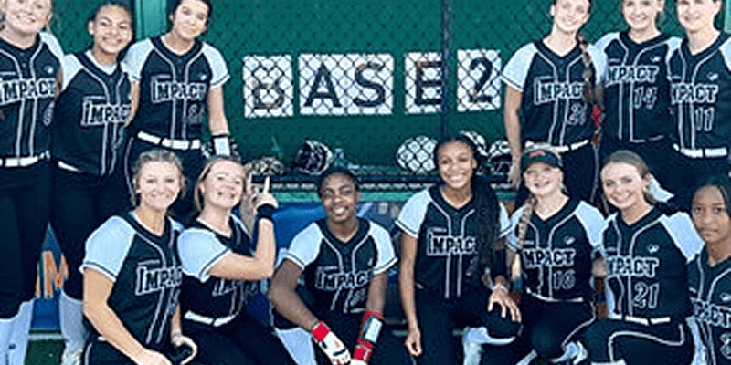 Softball team posing in front of fence.