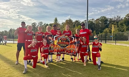 Red softball team posing with champions banner