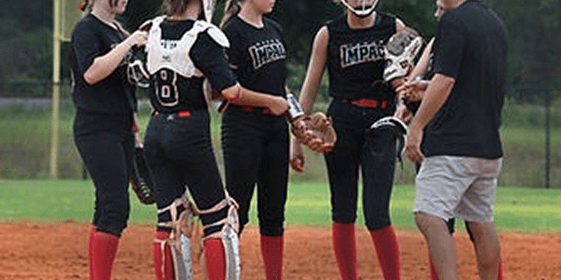 Softball players and coach huddling on field.