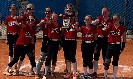 Softball team celebrating with a trophy.