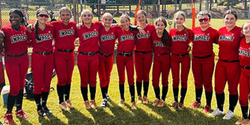 Softball team posing together on grass field.