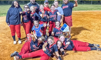 Youth softball team celebrating with trophy on field