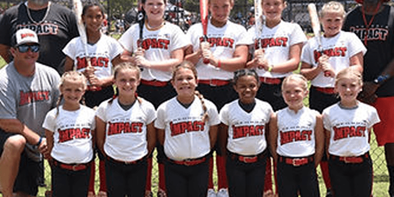 Youth softball team posing together outdoors.