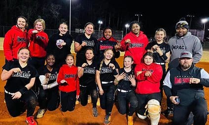 Softball team posing on the field, smiling.