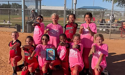 Youth softball team celebrating with trophy.