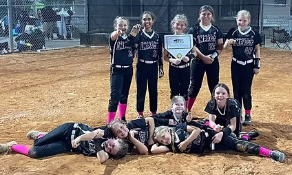 Girls' softball team celebrating with a trophy.