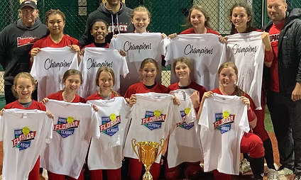 Girls softball team holding champions shirts and trophy
