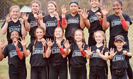 Girls' softball team posing and smiling together.