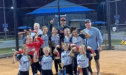 Girls' softball team celebrating with trophy.