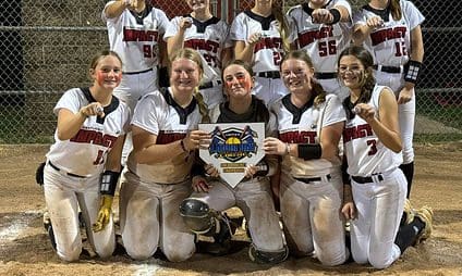 Softball team celebrating with championship plaque.