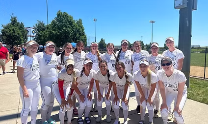 Softball team in white uniforms posing outdoors