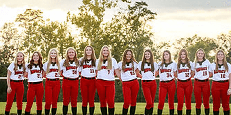 Softball team standing in red uniforms outdoors.