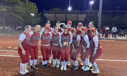 Softball team posing with a trophy at night.