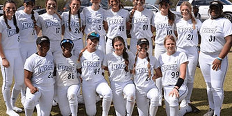 Women's softball team posing in white uniforms