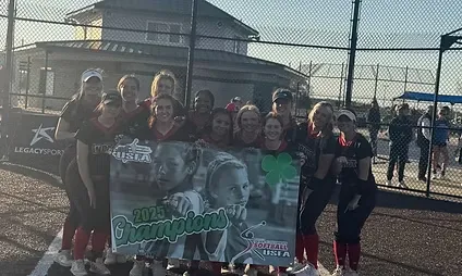 Softball team holding championship banner on field.