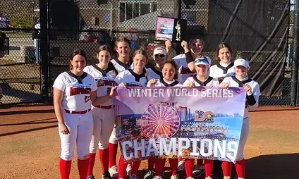 Softball team celebrating with championship banner.