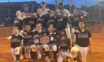 Softball team celebrating with championship belts.
