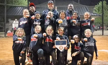 Youth softball team celebrating with a trophy.