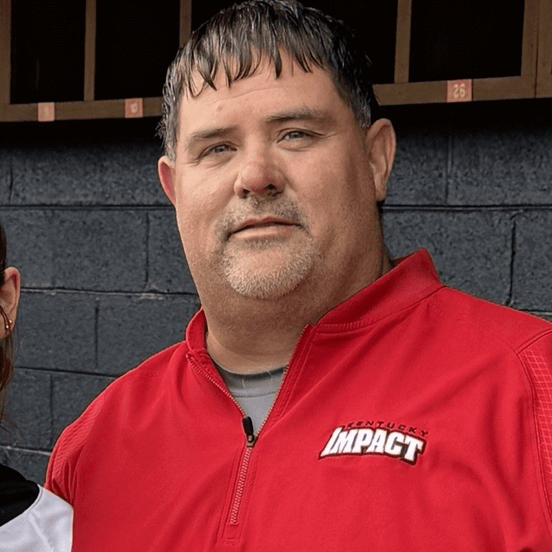 Man in a red Impact jacket posing outdoors.