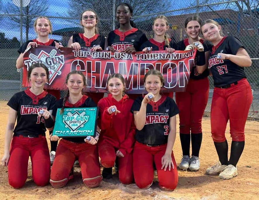 Youth softball team celebrating a championship victory with a banner.