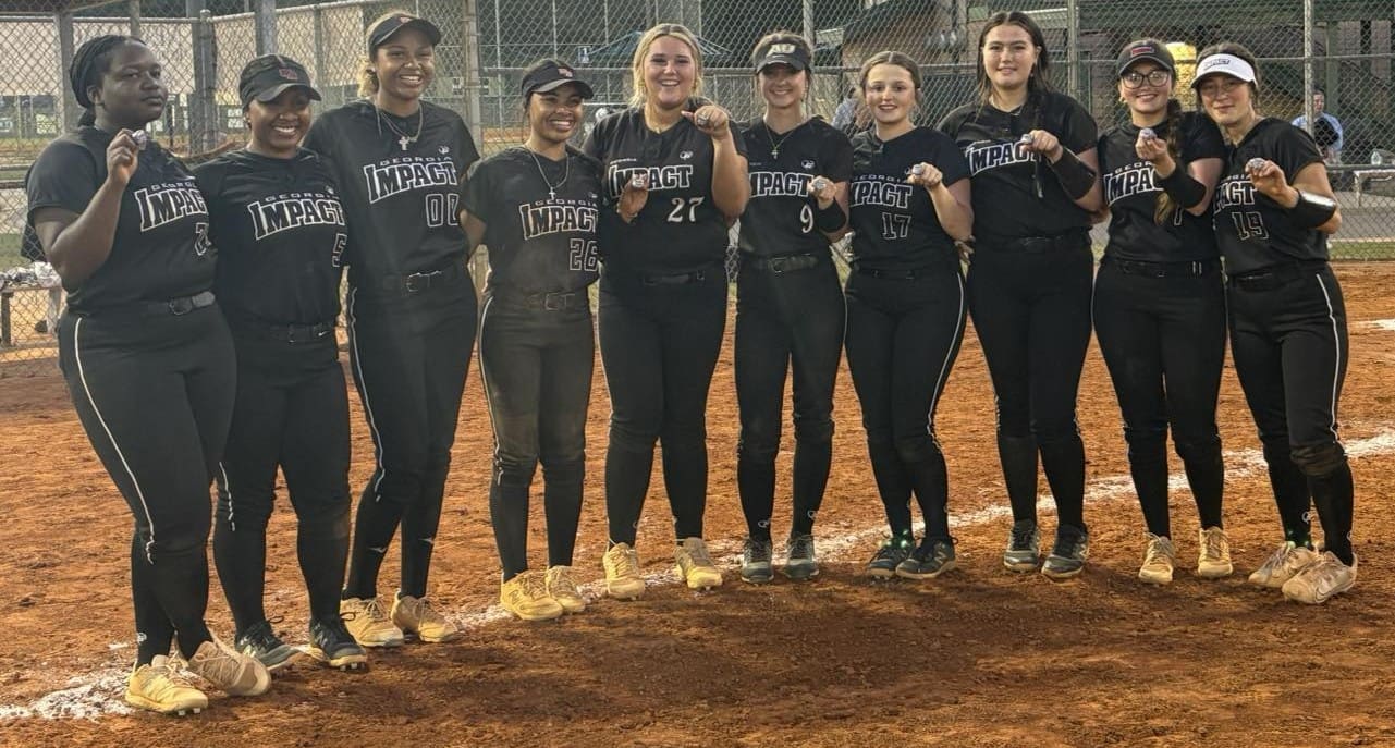 A softball team lined up with fists forward on the field.
