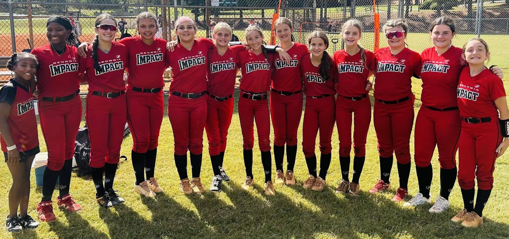 A group of young softball players in red uniforms posing for a team photo.
