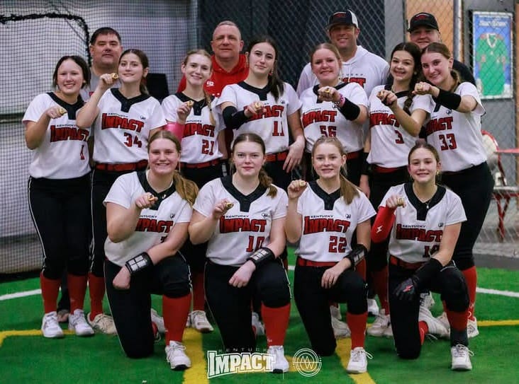 A girls' softball team posing for a group photo in their uniforms.