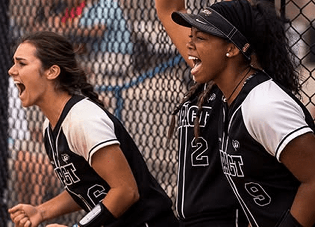 Two female softball players cheering enthusiastically during a game.