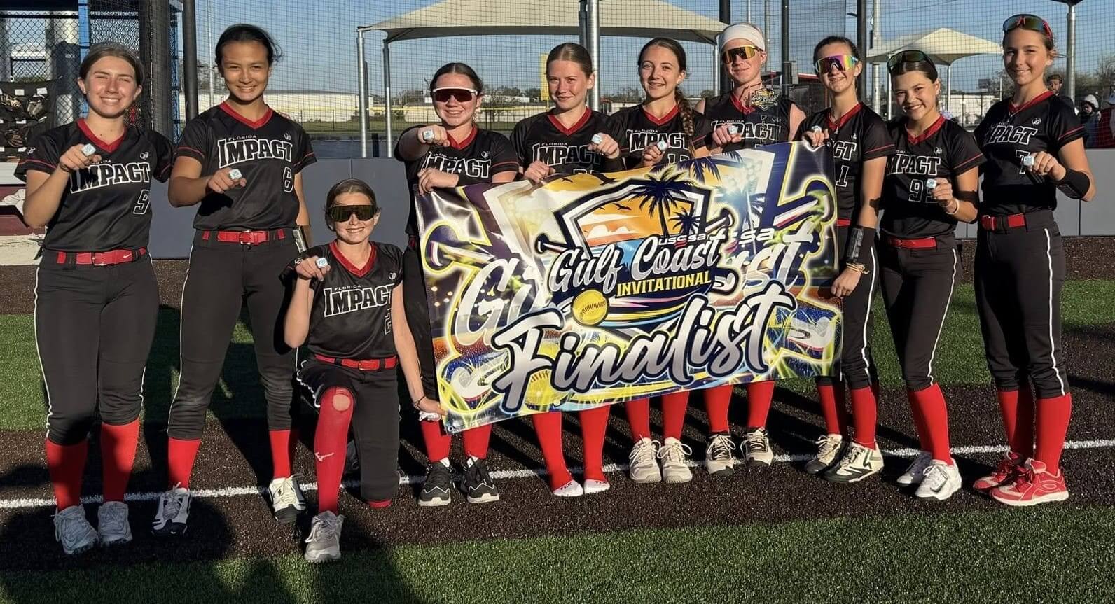 Youth softball team proudly holding their finalist banner on the field.