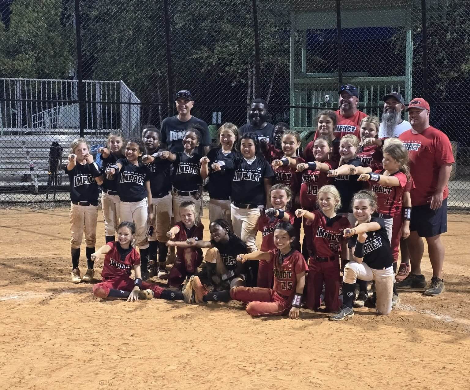 Youth baseball teams posing together on a dirt field after a game.