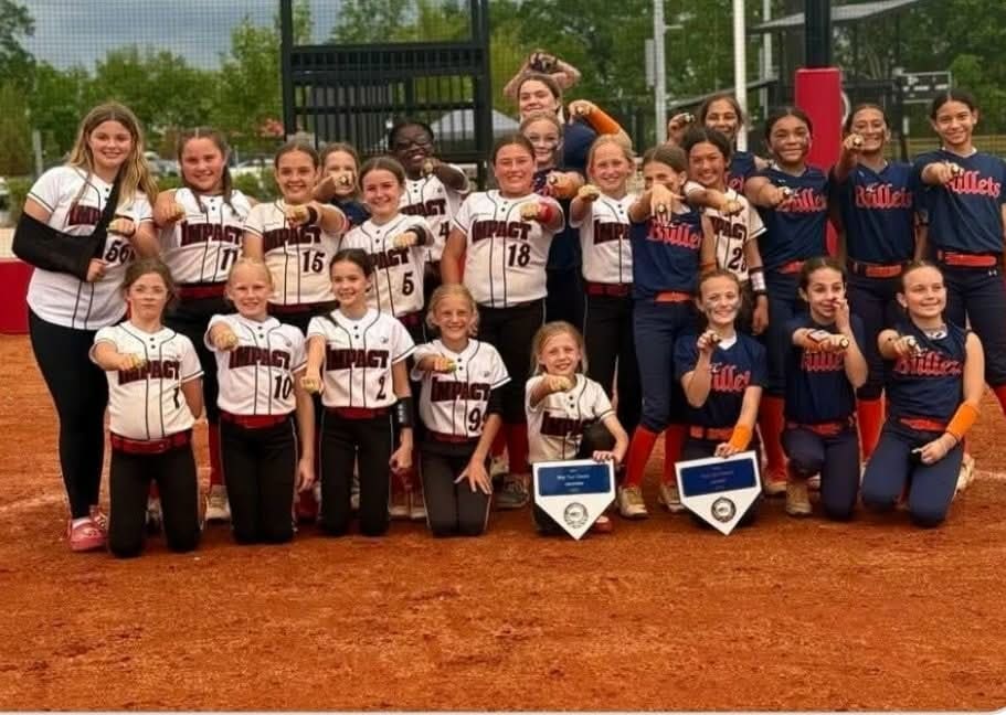 Youth baseball team posing together on the field with trophies and plaques.