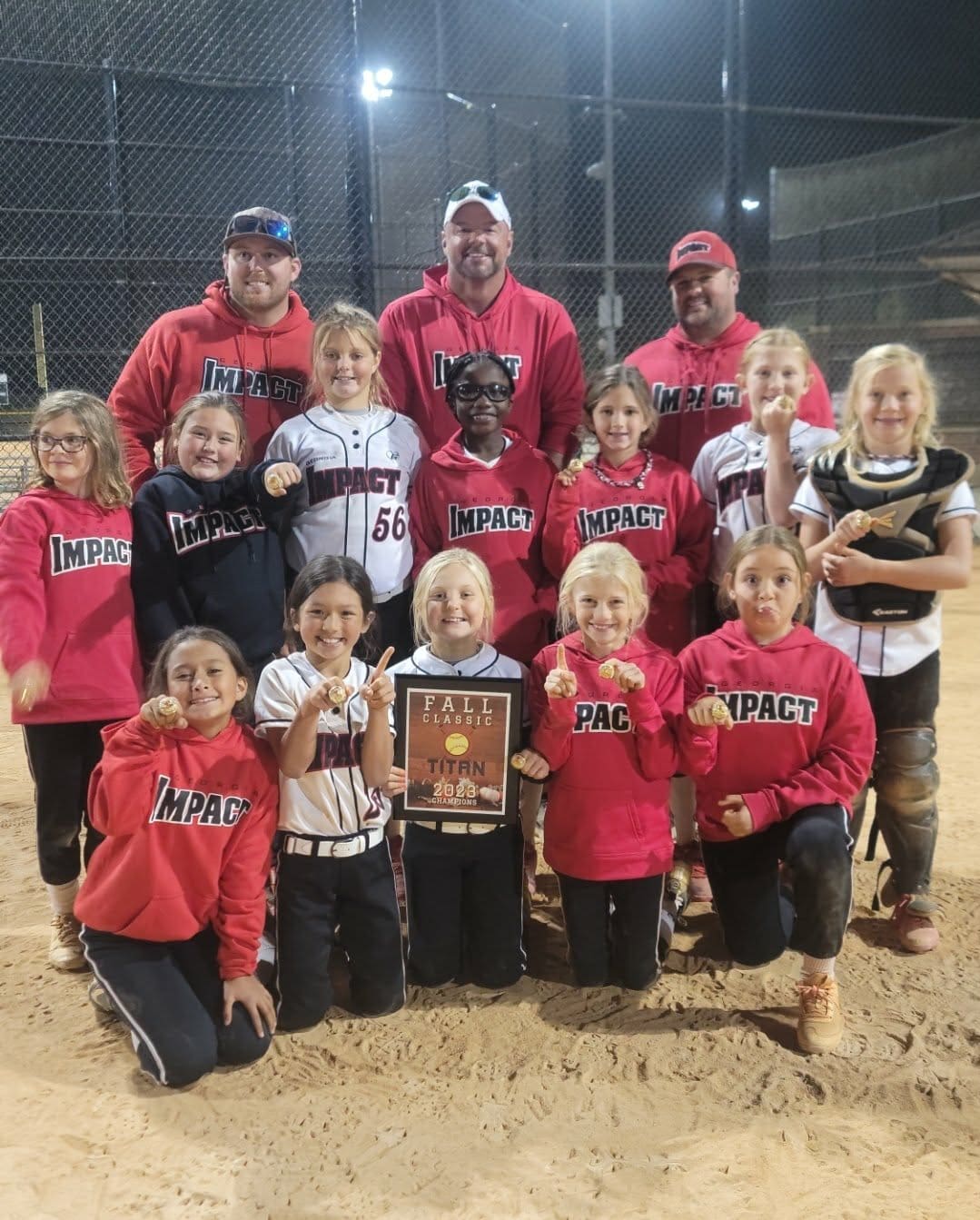 A youth baseball team with coaches proudly posing with trophies.