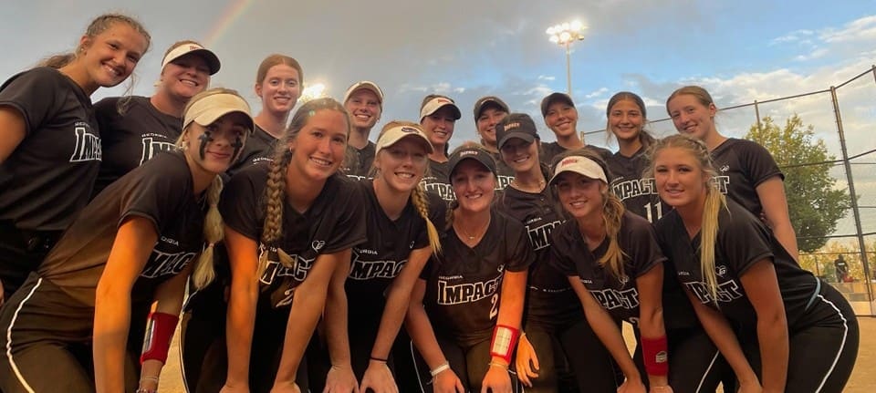 A group of smiling young women in matching athletic gear posing indoors.
