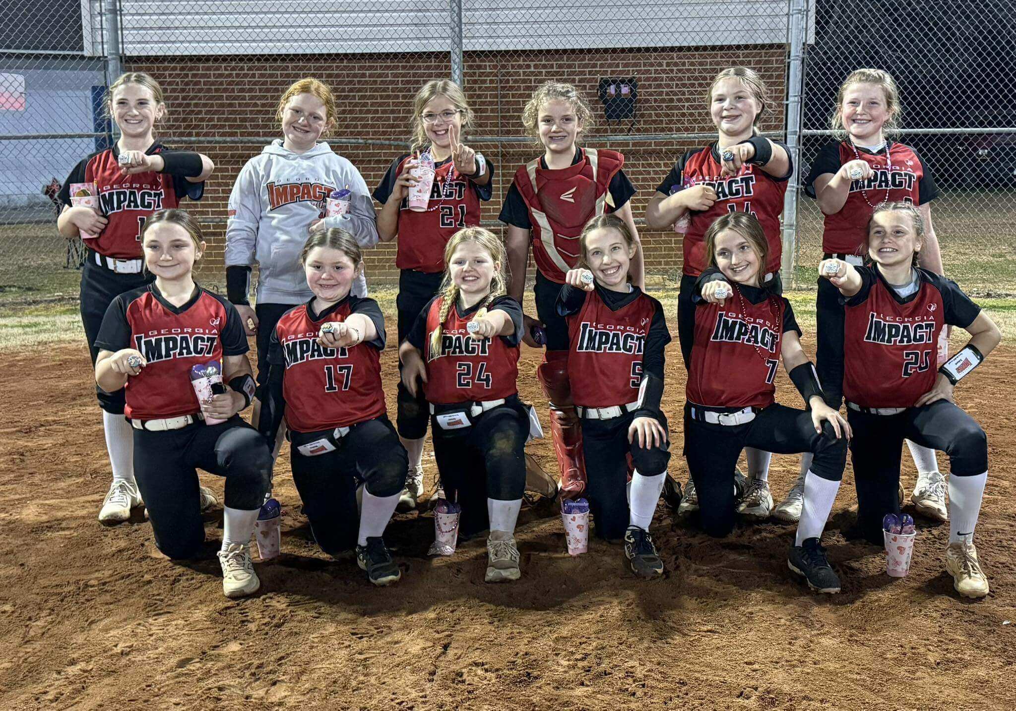 Girls softball team posing on dirt field