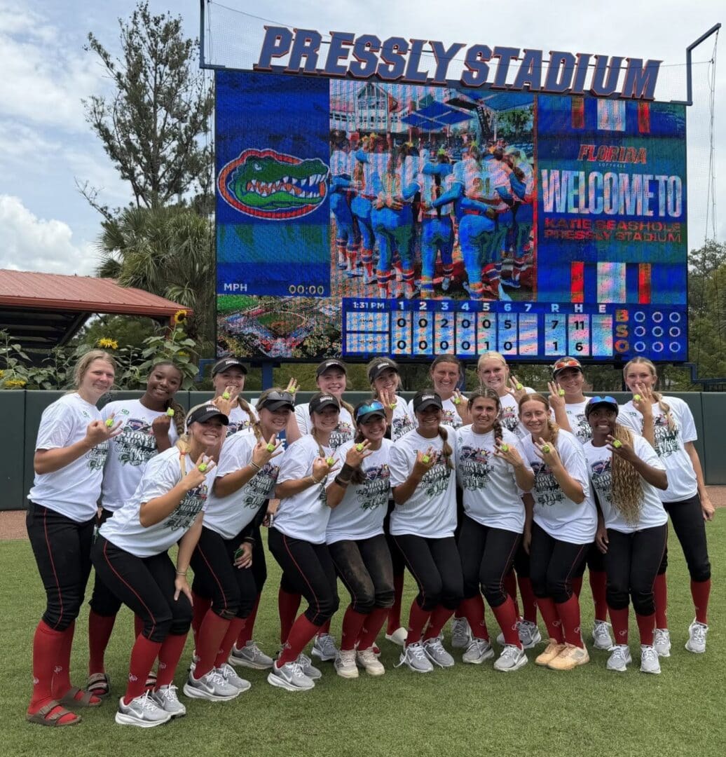 Softball team posing in front of scoreboard